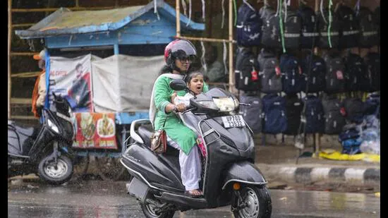 A-woman-and-a-child-ride-a-scooter-amid-rain-in-P_1783520379170